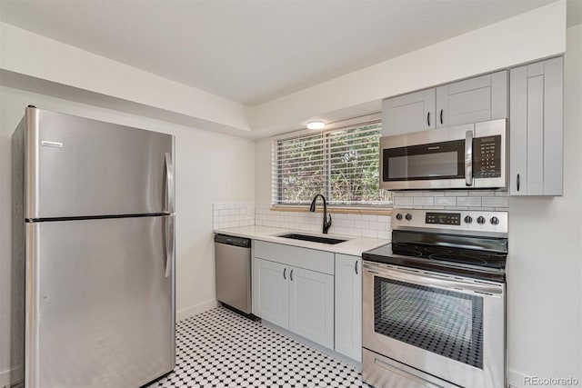 1331 Xanadu St, Aurora, CO 80011 - kitchen with appliances with stainless steel finishes, light countertops, gray cabinetry, tasteful backsplash, and light floors