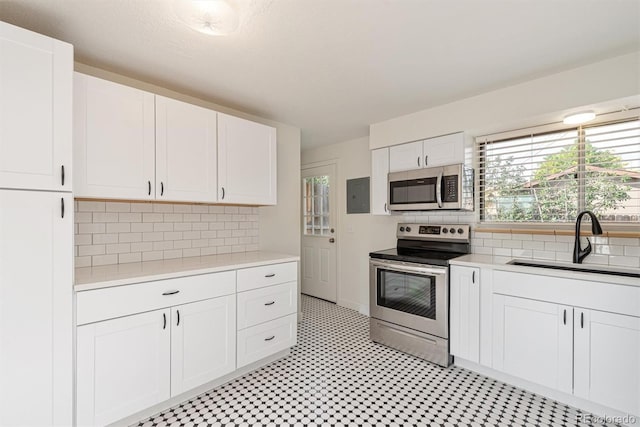 1331 Xanadu St, Aurora, CO 80011 - kitchen with stainless steel appliances, light countertops, electric panel, white cabinets, and backsplash