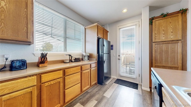 kitchen featuring dishwasher, black refrigerator, and light hardwood / wood-style floors