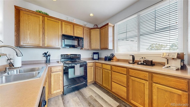 kitchen featuring a healthy amount of sunlight, sink, light hardwood / wood-style flooring, and black appliances