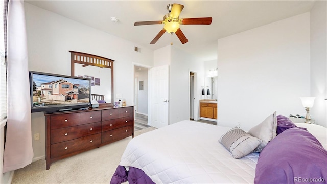 bedroom featuring ceiling fan, light colored carpet, and ensuite bath