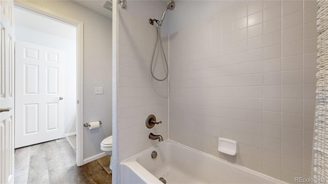 bathroom with tiled shower / bath, toilet, and hardwood / wood-style floors