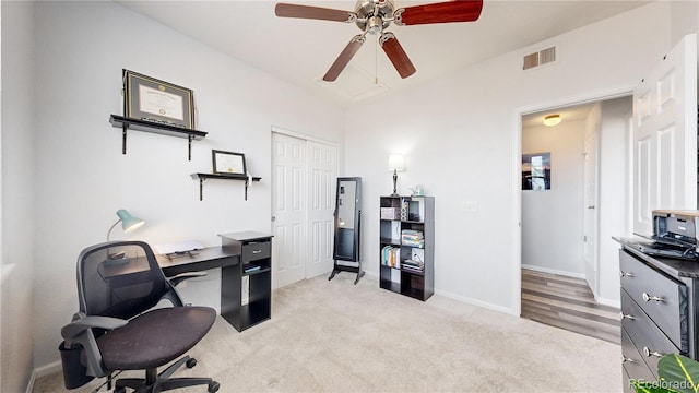 carpeted home office featuring ceiling fan