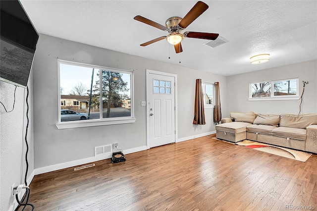 living room with ceiling fan, a healthy amount of sunlight, a textured ceiling, and hardwood / wood-style flooring