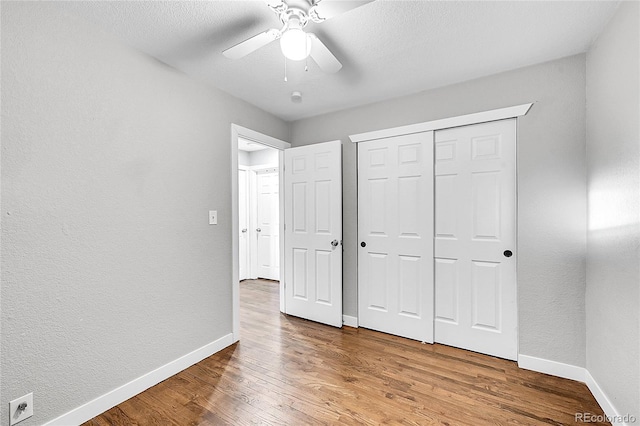 unfurnished bedroom with ceiling fan, a closet, and hardwood / wood-style flooring