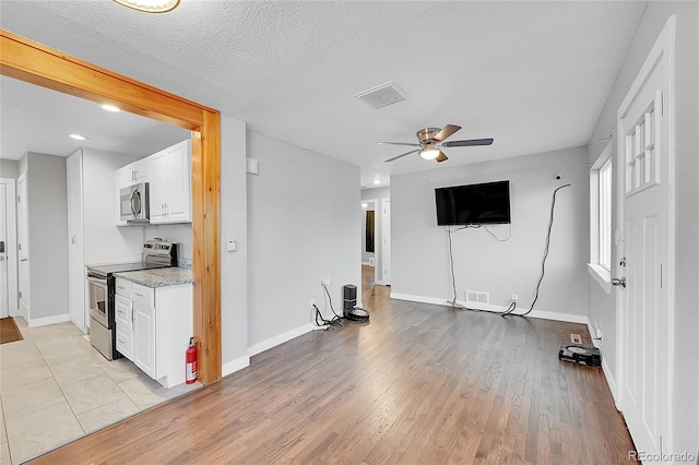 interior space featuring a textured ceiling, light wood-type flooring, and ceiling fan