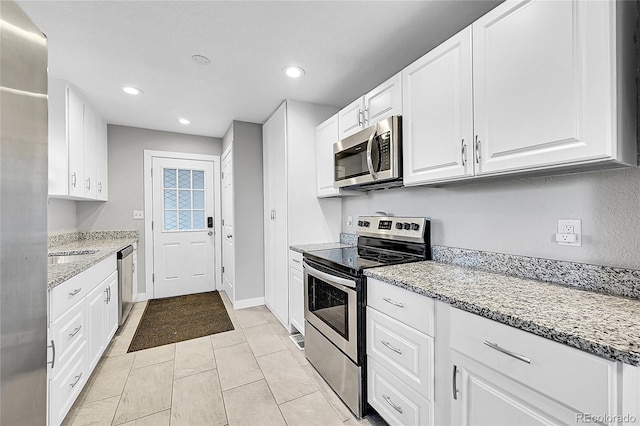 kitchen featuring light tile patterned flooring, stainless steel appliances, white cabinetry, and light stone counters