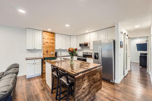 2286 S Pitkin Way Unit A, Aurora, CO 80013 - kitchen featuring stainless steel appliances, wooden counters, a barn door, open floor plan, and dark wood-style floors