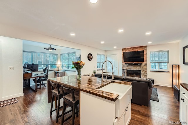 2286 S Pitkin Way Unit A, Aurora, CO 80013 - kitchen featuring open floor plan, a desk, dark wood finished floors, a fireplace, and white cabinets