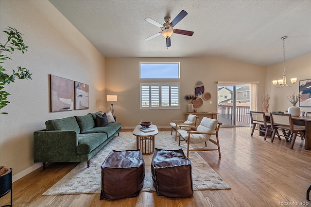 living room with ceiling fan with notable chandelier, light hardwood / wood-style flooring, a textured ceiling, and plenty of natural light