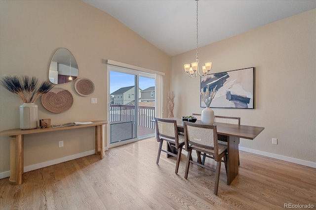 dining space with hardwood / wood-style flooring, lofted ceiling, and a notable chandelier