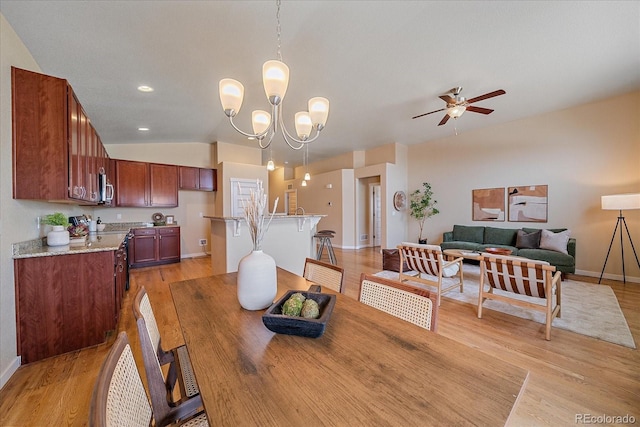 dining space featuring lofted ceiling, light hardwood / wood-style floors, and ceiling fan with notable chandelier