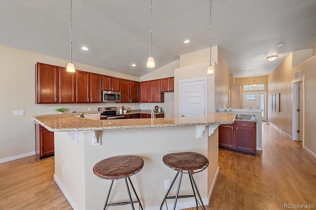 kitchen featuring pendant lighting, stainless steel appliances, a breakfast bar, and a center island with sink