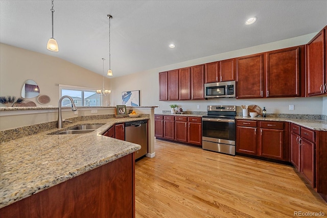 kitchen featuring lofted ceiling, sink, hanging light fixtures, appliances with stainless steel finishes, and light hardwood / wood-style floors