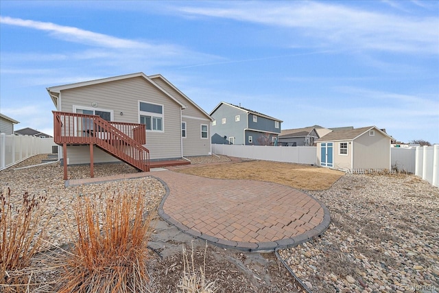 rear view of property featuring a deck, a shed, and a patio area