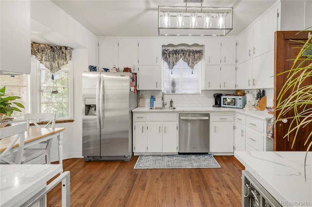 1475 S Monaco St Parkway, Denver, CO 80224 - kitchen with appliances with stainless steel finishes, white cabinets, dark wood finished floors, and decorative backsplash