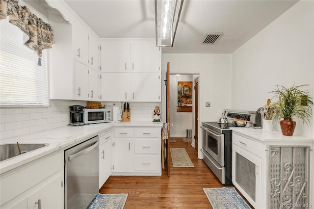 1475 S Monaco St Parkway, Denver, CO 80224 - kitchen with stainless steel appliances, decorative backsplash, light wood-style flooring, white cabinetry, and light stone counters