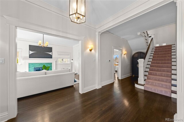 entrance foyer with a tiled fireplace, stairway, crown molding, and wood finished floors