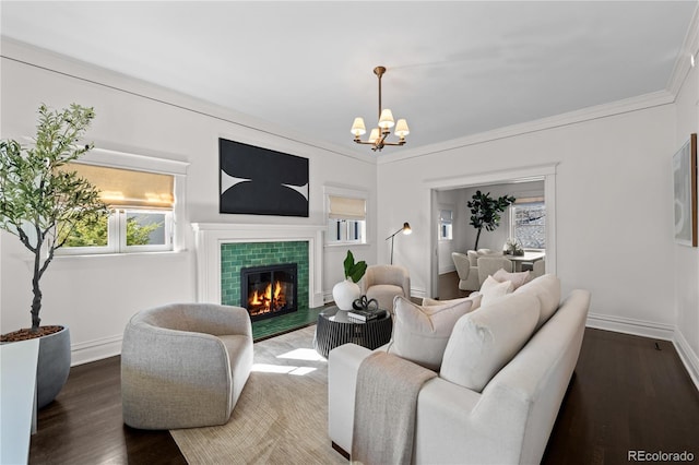 living room with baseboards, a tiled fireplace, ornamental molding, wood finished floors, and an inviting chandelier