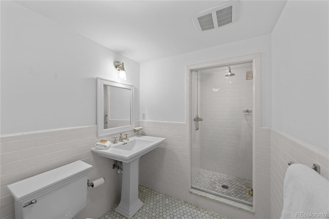 full bathroom featuring a stall shower, visible vents, tile walls, and wainscoting