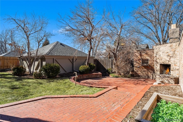 exterior space with an outdoor stone fireplace, fence, stone siding, a yard, and a patio area