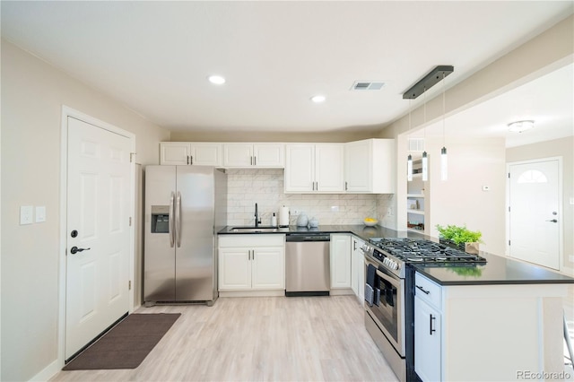 kitchen featuring stainless steel appliances, a peninsula, visible vents, white cabinets, and dark countertops