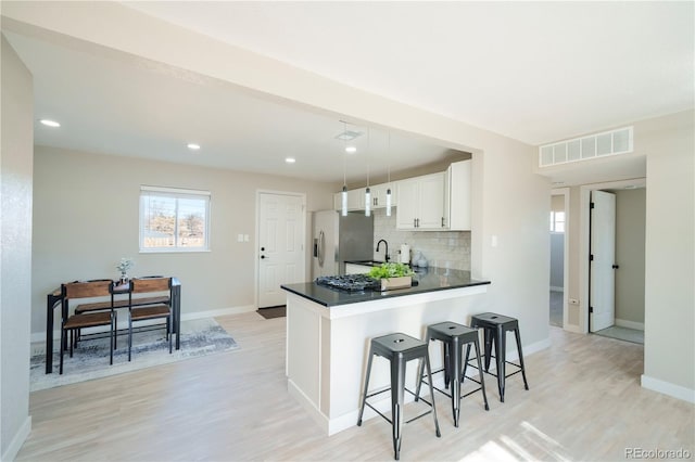 kitchen with tasteful backsplash, dark countertops, a breakfast bar area, white cabinetry, and a sink