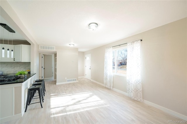 interior space featuring backsplash, dark countertops, a kitchen bar, and visible vents