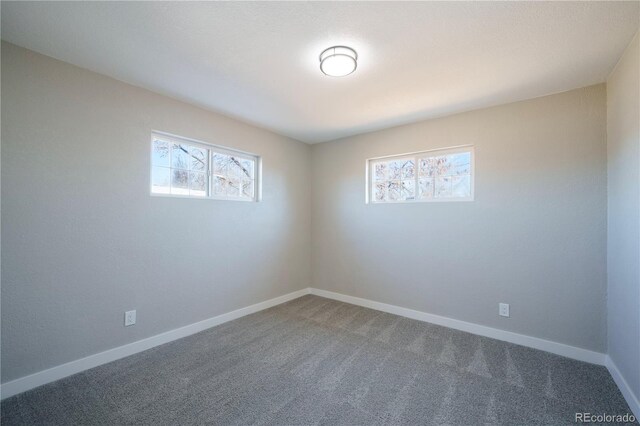 carpeted spare room featuring plenty of natural light and baseboards