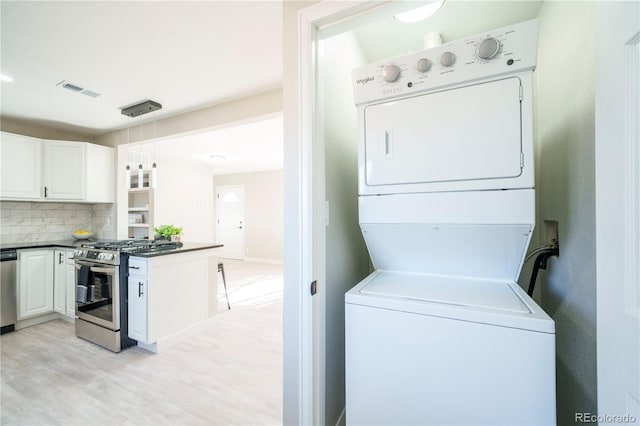 laundry area with laundry area, light wood-style floors, visible vents, and stacked washer / drying machine