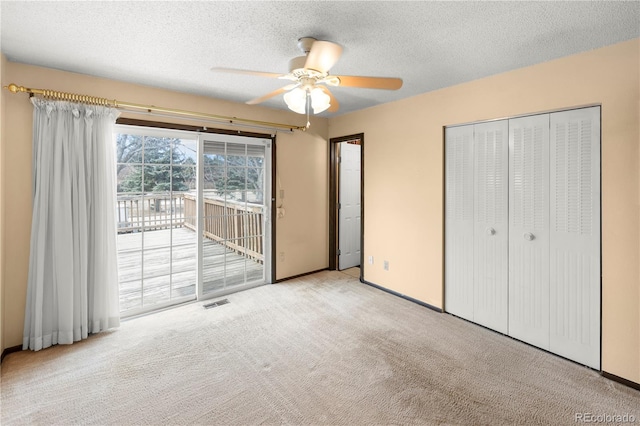 unfurnished bedroom with a ceiling fan, visible vents, carpet floors, access to exterior, and a textured ceiling