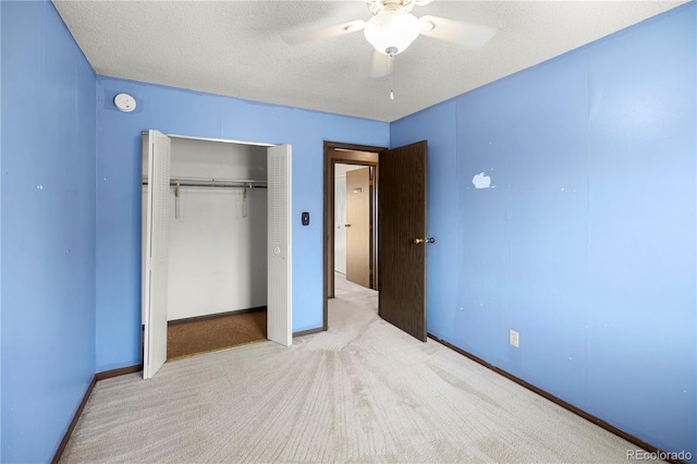 unfurnished bedroom featuring baseboards, carpet, a closet, a textured ceiling, and a ceiling fan