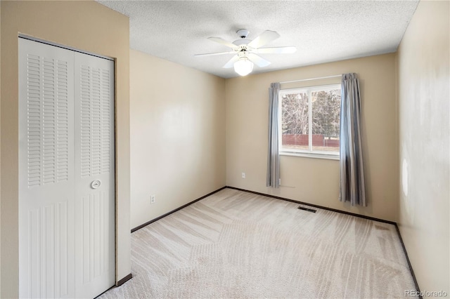 unfurnished bedroom featuring visible vents, ceiling fan, carpet, a closet, and a textured ceiling