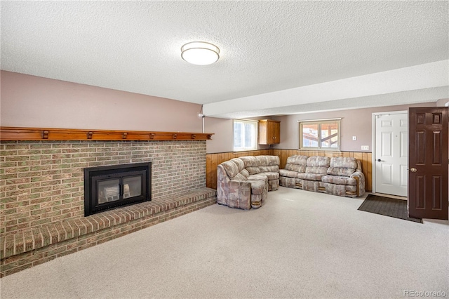 carpeted living room featuring a wainscoted wall, a textured ceiling, wood walls, and a fireplace