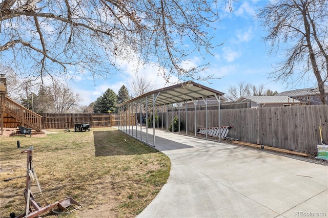 view of property's community featuring a fenced backyard, a lawn, a detached carport, and concrete driveway