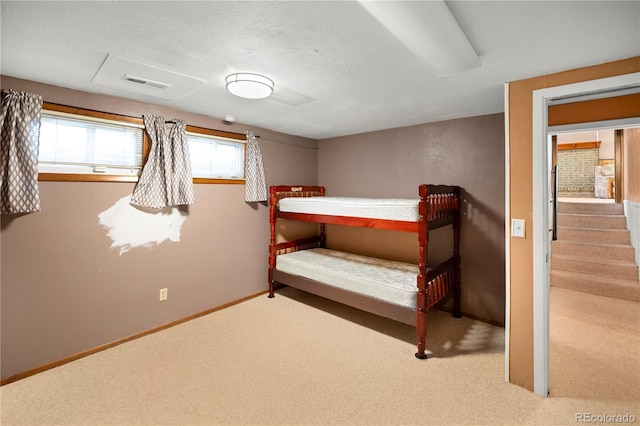 unfurnished bedroom with visible vents, a textured ceiling, baseboards, and carpet