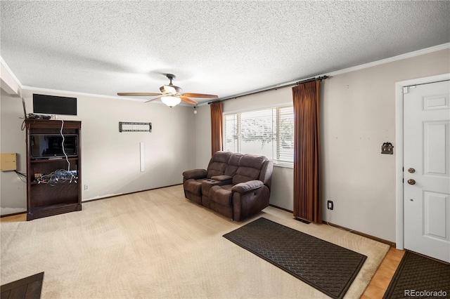 living room featuring light carpet, ornamental molding, a ceiling fan, and a textured ceiling