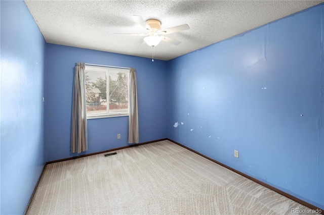 carpeted empty room featuring a textured ceiling, baseboards, visible vents, and ceiling fan