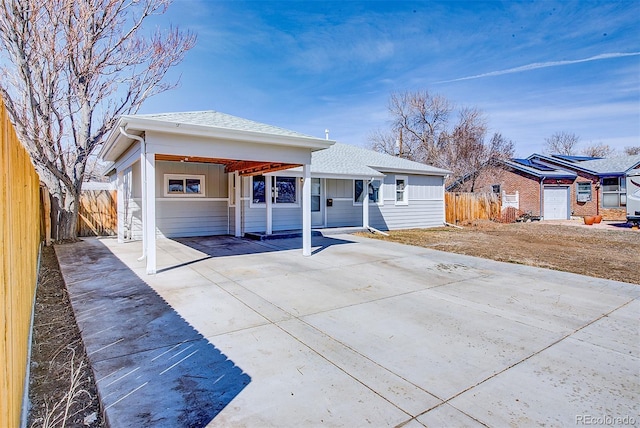 view of front of home with concrete driveway, fence, and roof with shingles