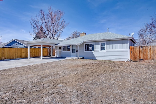 ranch-style house with an attached carport, fence, driveway, roof with shingles, and a chimney