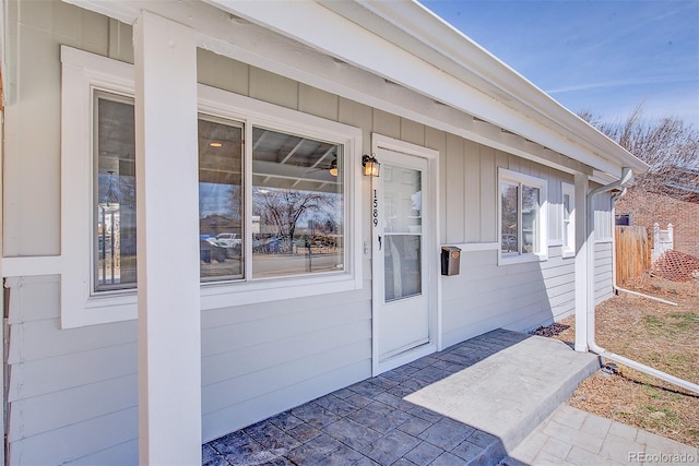 view of exterior entry featuring a patio area and fence