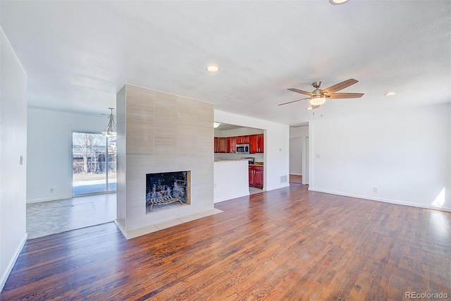 unfurnished living room featuring a ceiling fan, dark wood finished floors, recessed lighting, baseboards, and a tile fireplace