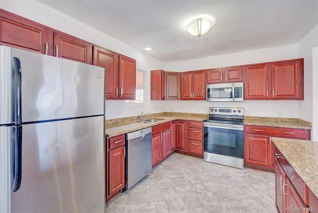 kitchen with reddish brown cabinets, appliances with stainless steel finishes, and a sink