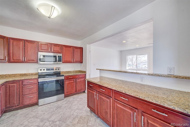 kitchen with light stone counters, stainless steel appliances, and reddish brown cabinets