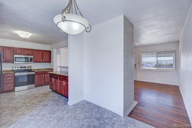 kitchen with baseboards, decorative light fixtures, light stone counters, appliances with stainless steel finishes, and reddish brown cabinets