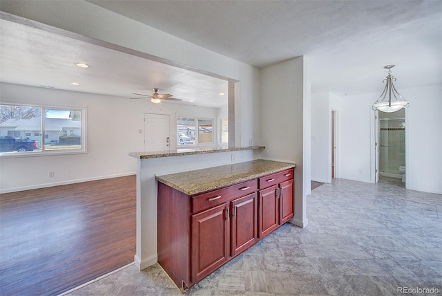 kitchen featuring hanging light fixtures, dark brown cabinets, light stone countertops, and baseboards