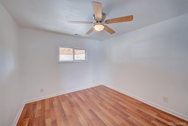 spare room featuring visible vents, a textured ceiling, light wood finished floors, baseboards, and ceiling fan