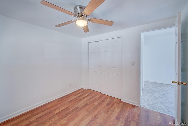 unfurnished bedroom featuring ceiling fan, light wood-style floors, a closet, and baseboards