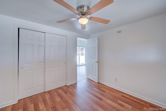 unfurnished bedroom featuring ceiling fan, a closet, baseboards, and light wood-style flooring