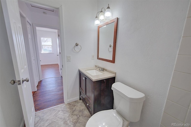 bathroom with vanity, toilet, and baseboards